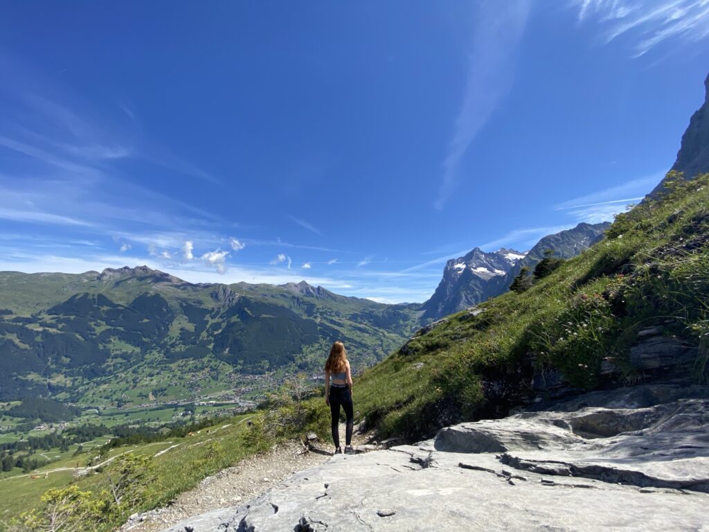 Hiking in Switzerland: Best Day Hikes in the Swiss Alps woman hiking in switzerland, the eiger trail in grindelwald village