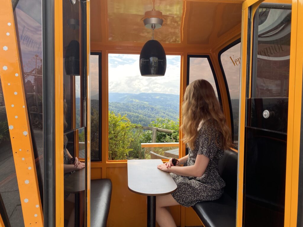 Hiking in Switzerland: Best Day Hikes in the Swiss Alps a woman setting at a cable car seating looking at the view of uetliberg mountain in zurich switzerland